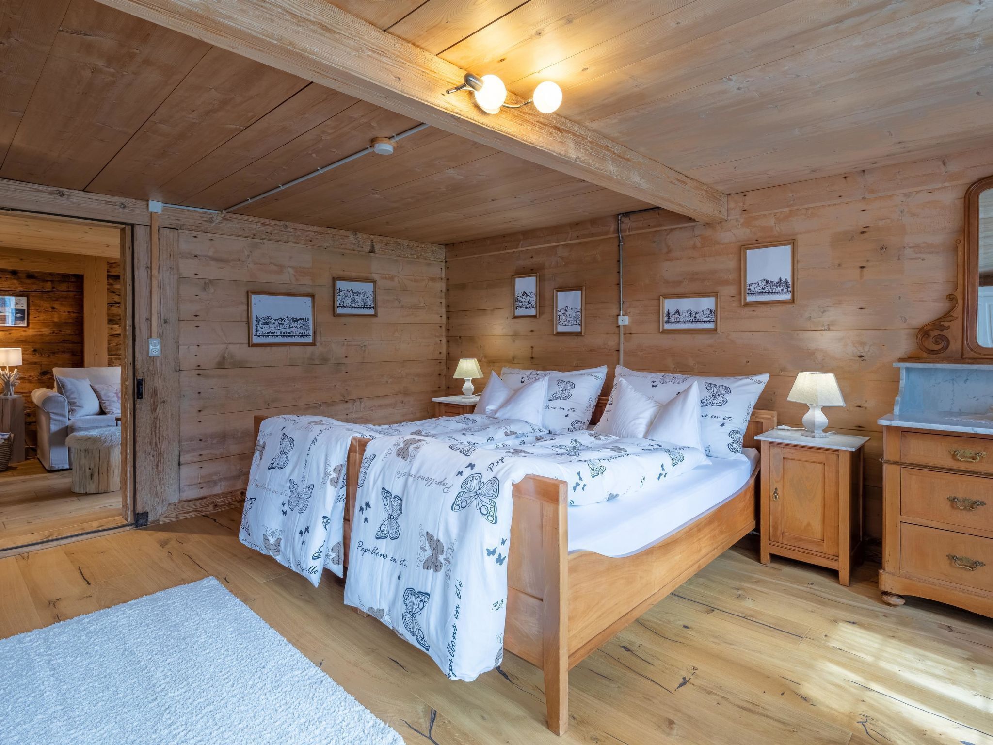 A wooden cabin room with a bed, bedside tables, and framed pictures on the walls.