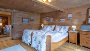 A wooden cabin room with a bed, bedside tables, and framed pictures on the walls. - Chalet Bijou+ 1 OG Appartement/Fewo, Dusche, WC, 2 Schlafräume by Interhome (Lenk)