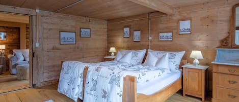 A wooden cabin room with a bed, bedside tables, and framed pictures on the walls.