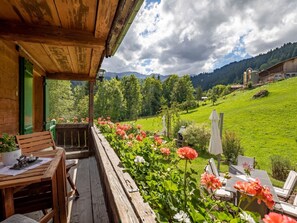 A wooden deck with a table and chairs, overlooking a lush green landscape with mountains in the distance. - Chalet Bijou+ 1 OG Appartement/Fewo, Dusche, WC, 2 Schlafräume by Interhome (Lenk)