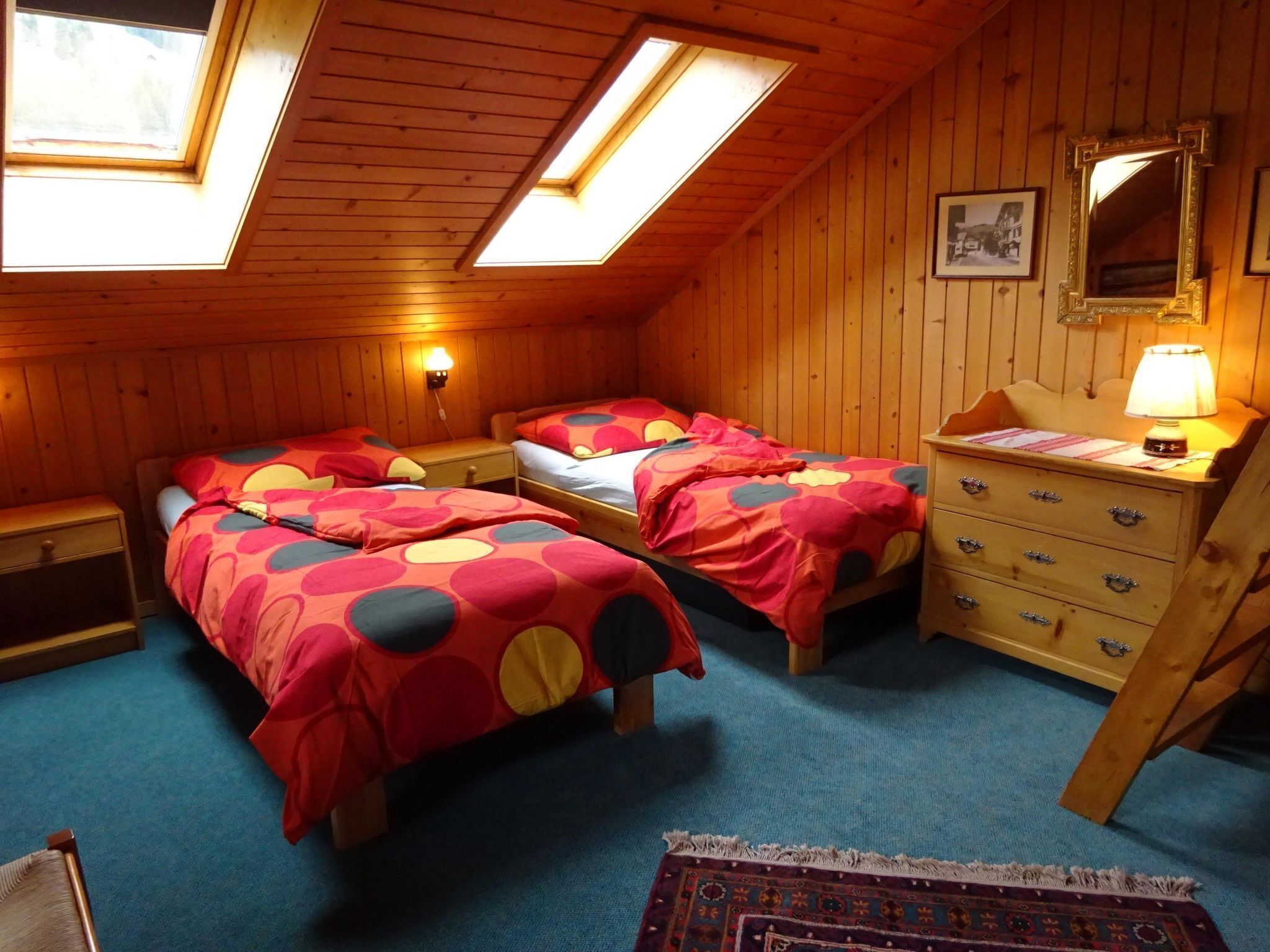 A room with two beds, a dresser, a mirror, and a skylight.