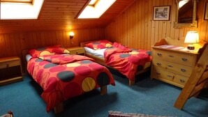 Ett rum med två sängar, en byrå, en spegel och ett takfönster.