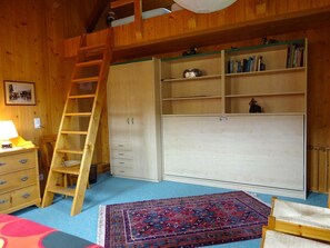 A room with a wooden ladder, a bookshelf, a desk, and a patterned rug. - Lischenhaus - Strubel Appartement/Fewo, Dusche oder Bad, WC, 2 Schlafräume by Interhome (Lenk)