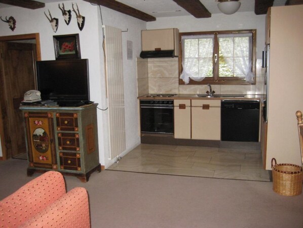 A compact living space with a kitchenette, a television, and a dining area.