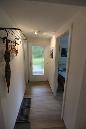 A narrow hallway with a wooden floor, a radiator, and a door leading to a room with a bed. - Chalet Claudia Appartement/Fewo, Dusche, 1 Schlafraum 2-Bett-Wohnung by Interhome (Lenk)
