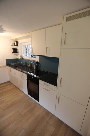A modern kitchen with white cabinetry, a black countertop, and a built-in oven. - Chalet Claudia Appartement/Fewo, Dusche, 1 Schlafraum 2-Bett-Wohnung by Interhome (Lenk)