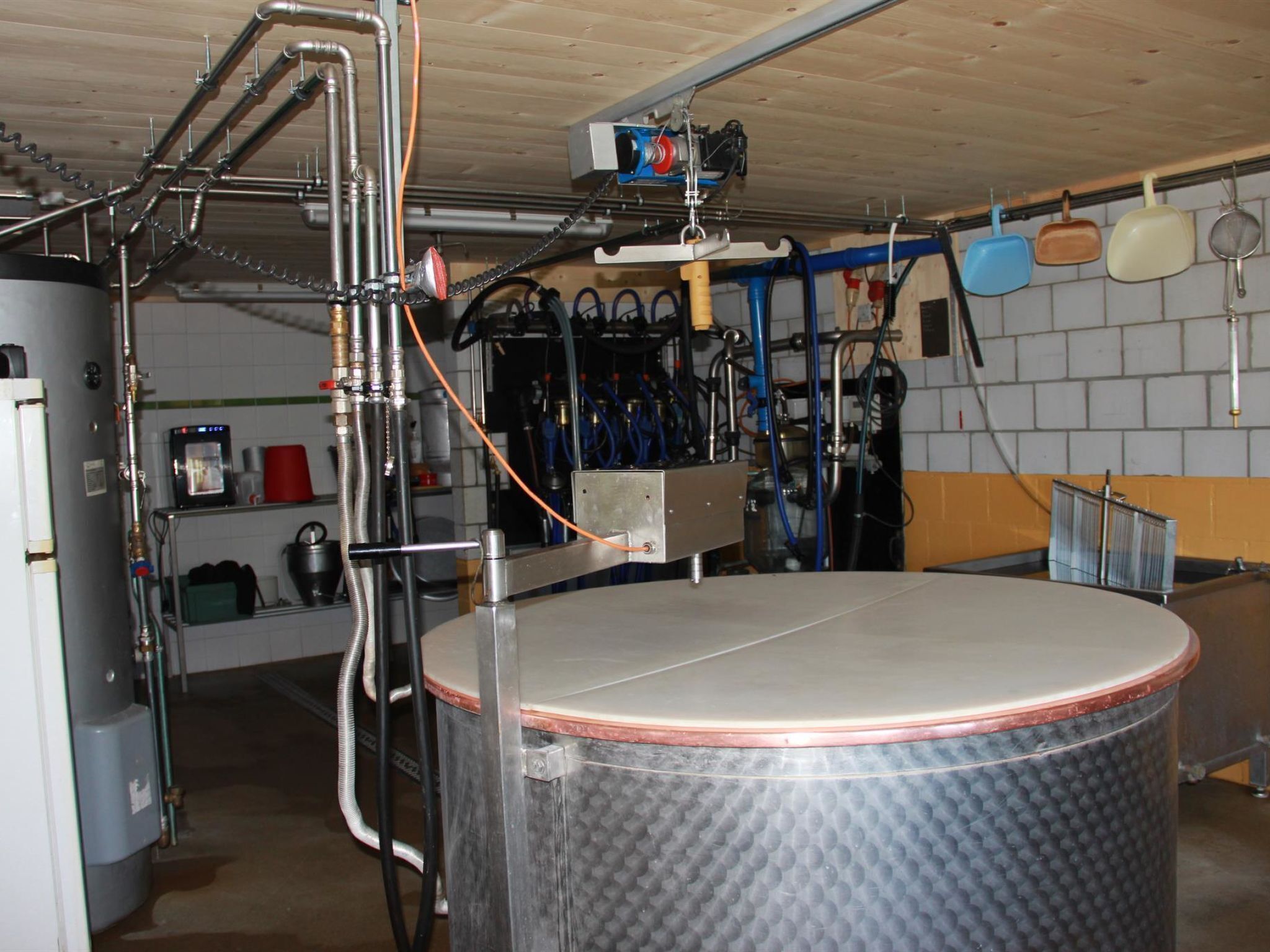A kitchen with stainless steel appliances, a large copper tank, and various hoses and pipes.