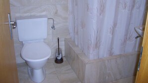 A bathroom with a toilet, a bidet, and a shower curtain. - Arnika # 1 Appartement/Fewo, Dusche oder Bad, WC, 1 Schlafraum by Interhome (Lenk)