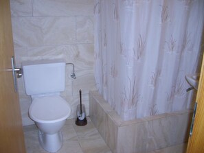 A bathroom with a toilet, a bidet, and a shower curtain. - Arnika # 1 Appartement/Fewo, Dusche oder Bad, WC, 1 Schlafraum by Interhome (Lenk)