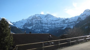 Un paysage de montagne avec des sommets enneigés et, au premier plan, un bâtiment doté d’un toit en pente.