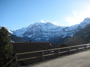 A mountain landscape with snow-covered peaks and a building with a sloped roof in the foreground. - Arnika # 1 Appartement/Fewo, Dusche oder Bad, WC, 1 Schlafraum by Interhome (Lenk)