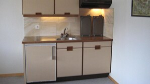 A compact kitchen with a sink, cabinets, and a stove. - Arnika # 1 Appartement/Fewo, Dusche oder Bad, WC, 1 Schlafraum by Interhome (Lenk)