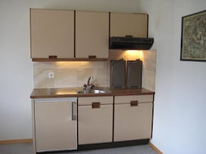 A compact kitchen with a sink, cabinets, and a stove. - Arnika # 1 Appartement/Fewo, Dusche oder Bad, WC, 1 Schlafraum by Interhome (Lenk)
