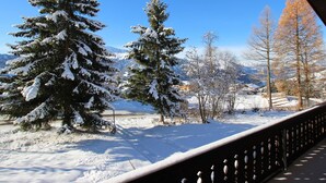Un paisaje nevado con árboles cubiertos de nieve y montañas al fondo.