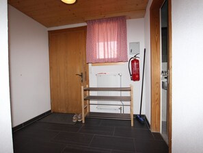A hallway with a wooden door, a radiator, a fire extinguisher, and a shoe rack. - Möösli Appartement/Fewo, Dusche oder Bad, WC, 4 oder mehr Schlafräume by Interhome (Lenk)
