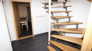 Una escalera de madera con barandillas metálicas que conduce a una habitación con una silla y una mesa.