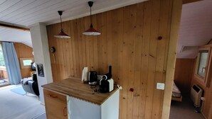 A compact kitchen with wooden panel walls, a small countertop, and two pendant lights. - Wildbach Appartement/Fewo, Dusche oder Bad, WC, 2 Schlafräume 4-Bett-Wohnung by Interhome (Lenk)
