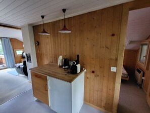 Eine kleine Küche mit Holzwandverkleidung, einer Arbeitsplatte und zwei Pendelleuchten.