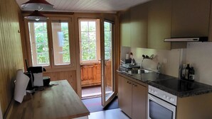 A compact kitchen with a stove, sink, and a dining area with a table and chairs. - Wildbach Appartement/Fewo, Dusche oder Bad, WC, 2 Schlafräume 4-Bett-Wohnung by Interhome (Lenk)