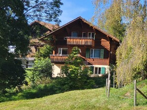 A two-story wooden house with a balcony, surrounded by greenery and trees. - Wildbach Appartement/Fewo, Dusche oder Bad, WC, 2 Schlafräume 4-Bett-Wohnung by Interhome (Lenk)
