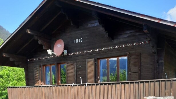 Et toetagers træhus med en balkon, en parabolantenne og en terrasse med havemøbler.