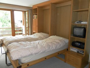 Ein Schlafzimmer mit einem Bett, einem Fernseher und einem Holzschrank.