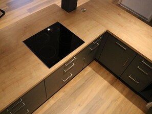 A kitchen with a black induction cooktop, wooden cabinets, and a stainless steel sink. - am Lee Appartement/Fewo, Dusche und Bad, WC, 2 Schlafräume 6-Bettwohnung by Interhome (Lenk)