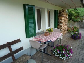 An outdoor seating area with a table and chairs, a bench, and potted plants. - Bach Appartement/Fewo, Dusche oder Bad, WC, 1 Schlafraum 2-Bett-Wohnung by Interhome (Lenk)