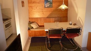 A compact room with a wooden wall, a bench, a table with chairs, and a hanging light fixture. - Bach Appartement/Fewo, Dusche oder Bad, WC, 1 Schlafraum 2-Bett-Wohnung by Interhome (Lenk)