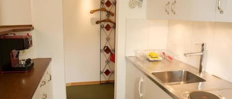 A kitchen with white cabinets, a stainless steel sink, and a coffee machine.