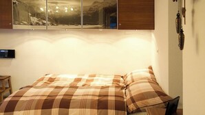 A bed with a plaid bedspread, a bedside table, and a wall-mounted telephone. - Pony 4-Bettwohnung Appartement/Fewo, Dusche oder Bad, WC, 1 Schlafraum by Interhome (Lenk)