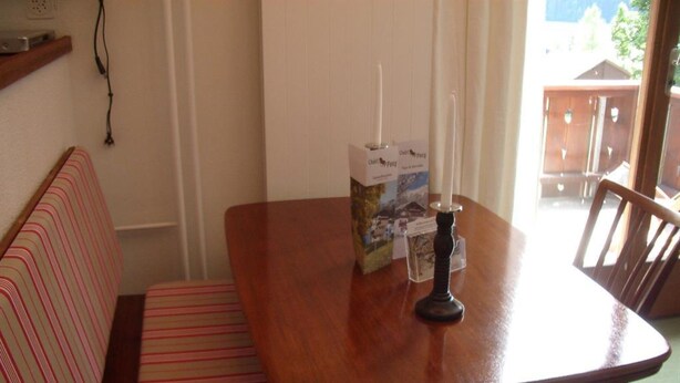 A dining area with a wooden table, a bench, and a candle. - Pony 4-Bettwohnung Appartement/Fewo, Dusche oder Bad, WC, 1 Schlafraum by Interhome (Lenk)