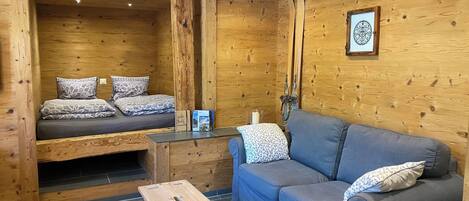 A wooden interior with a bed, a sofa, and a small table.