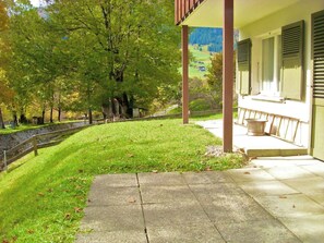 Ein Haus mit überdachter Veranda, einem gepflasterten Weg und einem Rasen mit Bäumen.