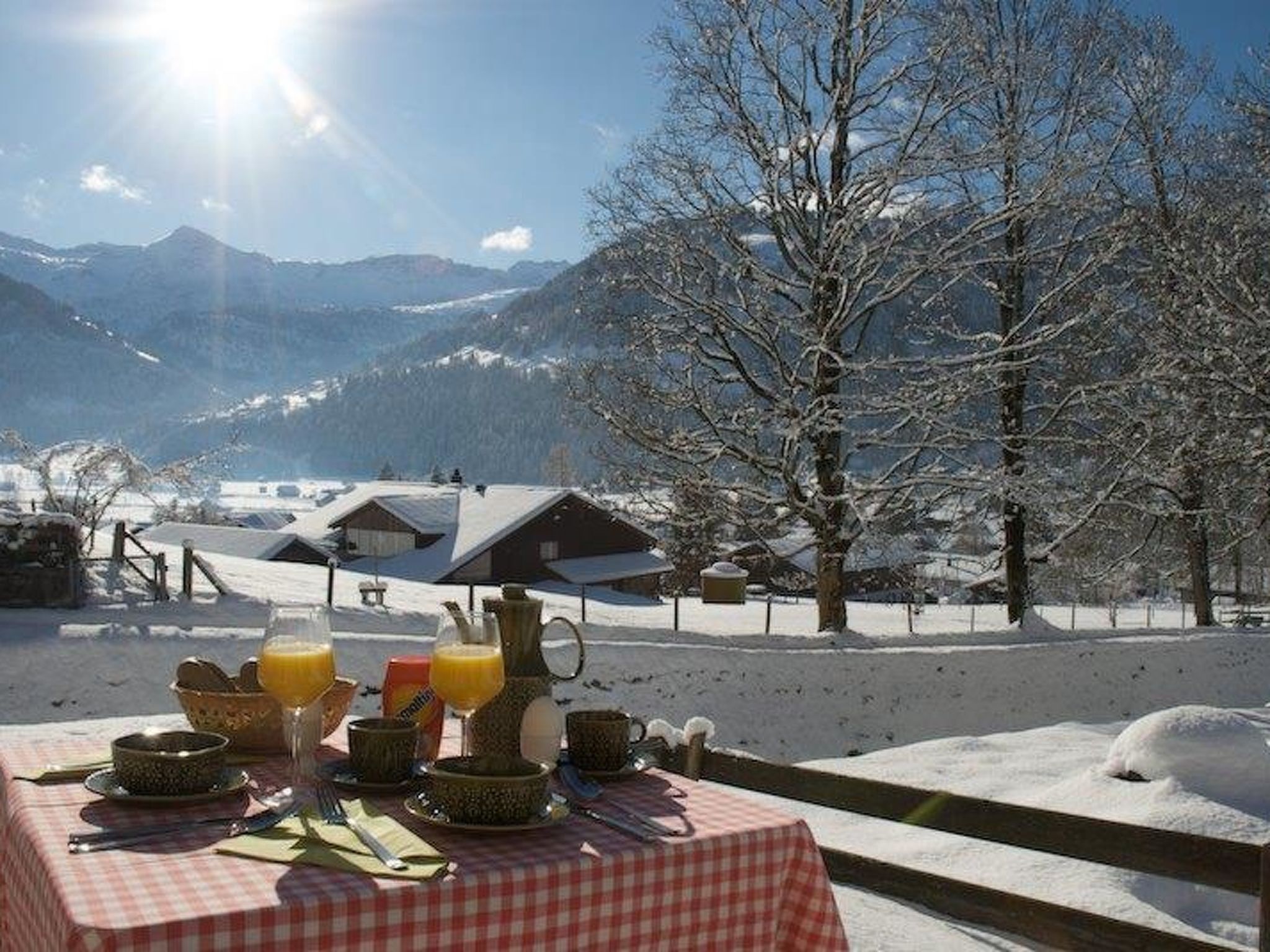 A table set outdoors with a mountain view, a clear sky, and snow-covered ground.