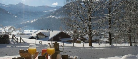 A table set outdoors with a mountain view, a clear sky, and snow-covered ground.