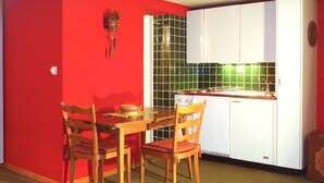 Comedor con pared roja, una mesa de madera y dos sillas.