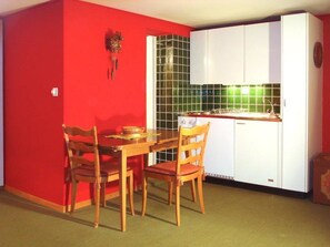 Ein Essbereich mit roter Wand, einem Holztisch und zwei Stühlen.