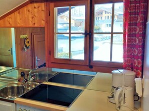 A kitchen with a double sink, a coffee maker, and a view of a building through a window. - Bärnermutz # 2 Appartement/Fewo, Dusche oder Bad, WC, 2 Schlafräume by Interhome (Lenk)
