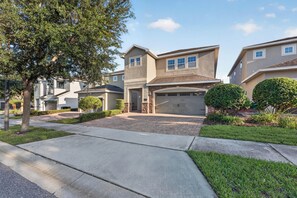 A residential street with modern two-story houses, a driveway, and well-maintained lawns. - 6BR Encore w/ Under-the-Sea Kids' Room & Pool (Kissimmee)