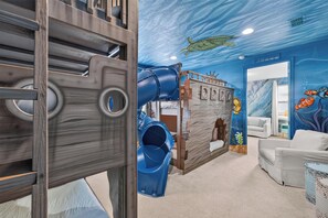 Un espace de jeux pour enfants avec un toboggan, une cabane et une fresque représentant une tortue de mer.