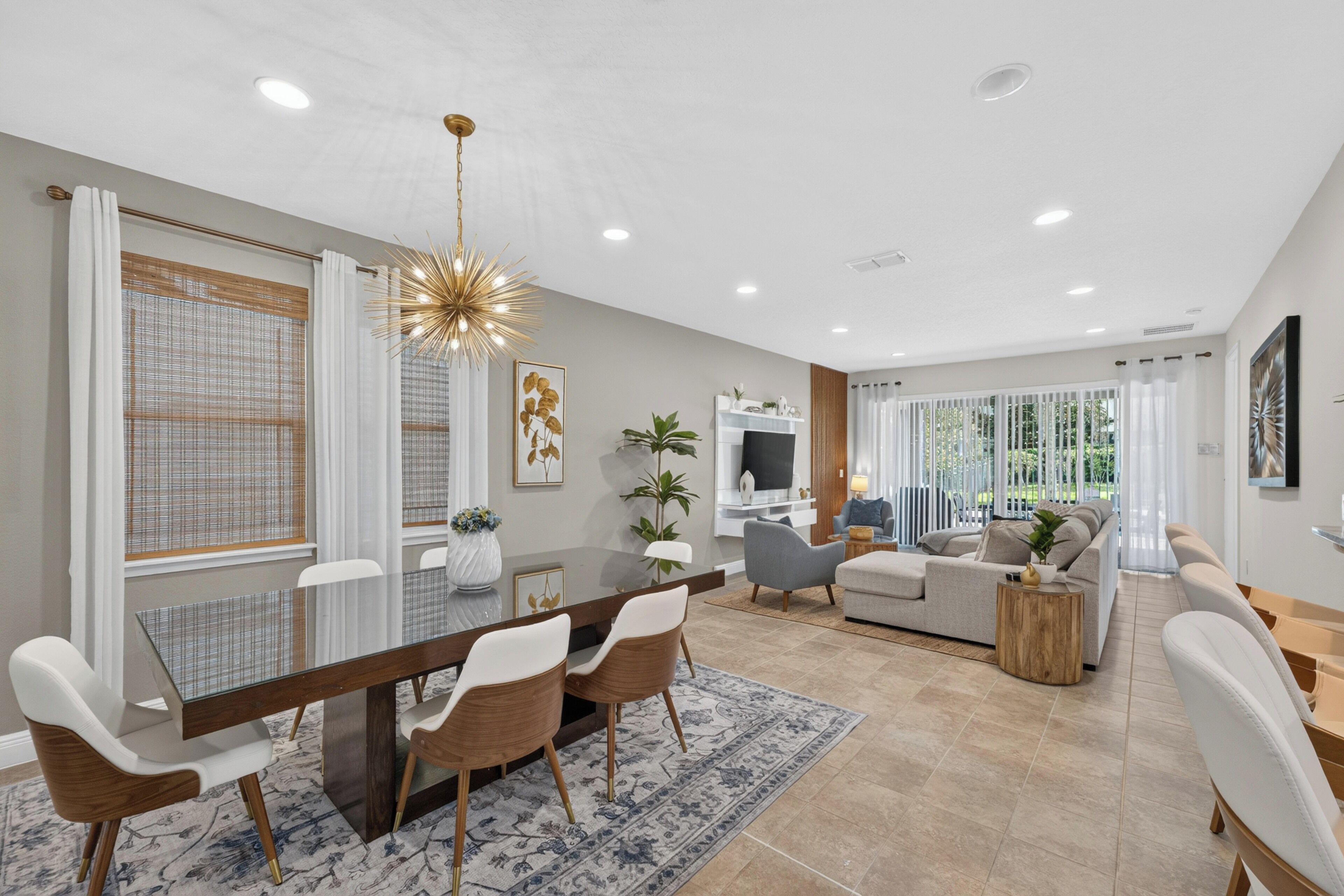 A modern living room with a sofa, a dining table with chairs, and a TV.