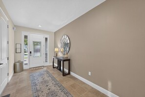 A hallway with a door, a console table with a lamp, a rug, and a wall-mounted decorative piece. - 6BR Encore w/ Under-the-Sea Kids' Room & Pool (Kissimmee)