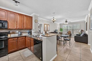 A kitchen with wooden cabinets, a microwave, and a dishwasher. - Bella Piazza Serenade | 3BR/3BA Davenport, Balcony (Davenport)