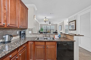 A kitchen with granite countertops, wooden cabinets, a dishwasher, and a coffee maker. - Bella Piazza Serenade | 3BR/3BA Davenport, Balcony (Davenport)
