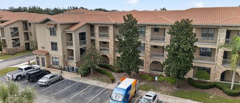 A multi-story hotel with a parking lot, a delivery truck, and a white car.