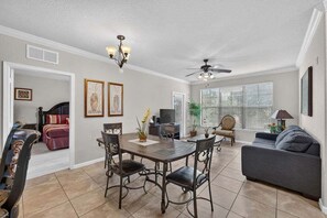 A dining area with a table and chairs, a ceiling fan, and a television. - Bella Piazza Serenade | 3BR/3BA Davenport, Balcony (Davenport)