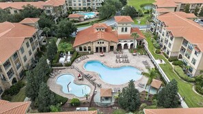 A hotel with a central courtyard featuring a swimming pool, lounge areas, and a small building with a red-tiled roof. - Bella Piazza Serenade | 3BR/3BA Davenport, Balcony (Davenport)