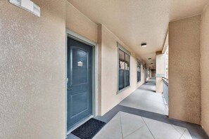 Un couloir avec une porte portant le numéro « 322 » et une fenêtre avec des stores.