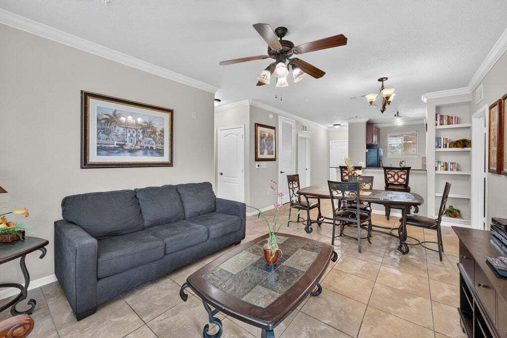 Ein Wohnzimmer mit grauem Sofa, einem Couchtisch und einem Essbereich mit Tisch und Stühlen.
